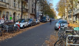 Straße mit geparkten Autos und Fahrrädern an Fahrradständern