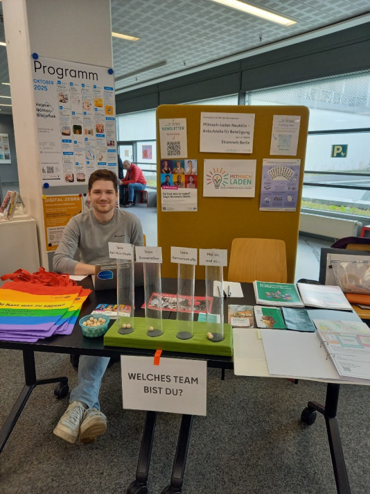 Person sitzt hinter einem Tisch auf dem Flyer und Werbegeschenke liegen