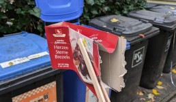 Mülltonnen und eine leere Packung Lebkuchen, die mit einer Zange aufgehoben wurde