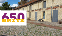 Kopfsteinpflaster und Gebäude im Hintergrund und Schriftzug 650 Britz in lila und gelb links