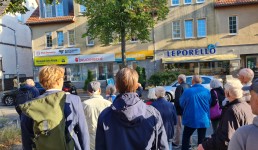 Mehrere Menschen stehen vor einer Häuserfassade auf der der Schriftzug Leporello zu sehen ist