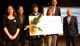 Mehrere Menschen, die einen überdimensionalen Scheck in die Kamera halten