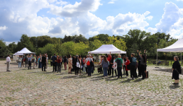 Gruppe von Menschen unter weißen Pavillons auf einem Platz im Freien
