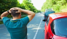 Mann steht an Straße und guckt wegfahrendem Auto hinterher