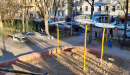 Spielplatz umgeben von Bäumen, Häuser im Hintergrund